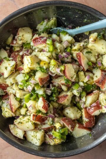 Potato salad being mixed together in a bowl.