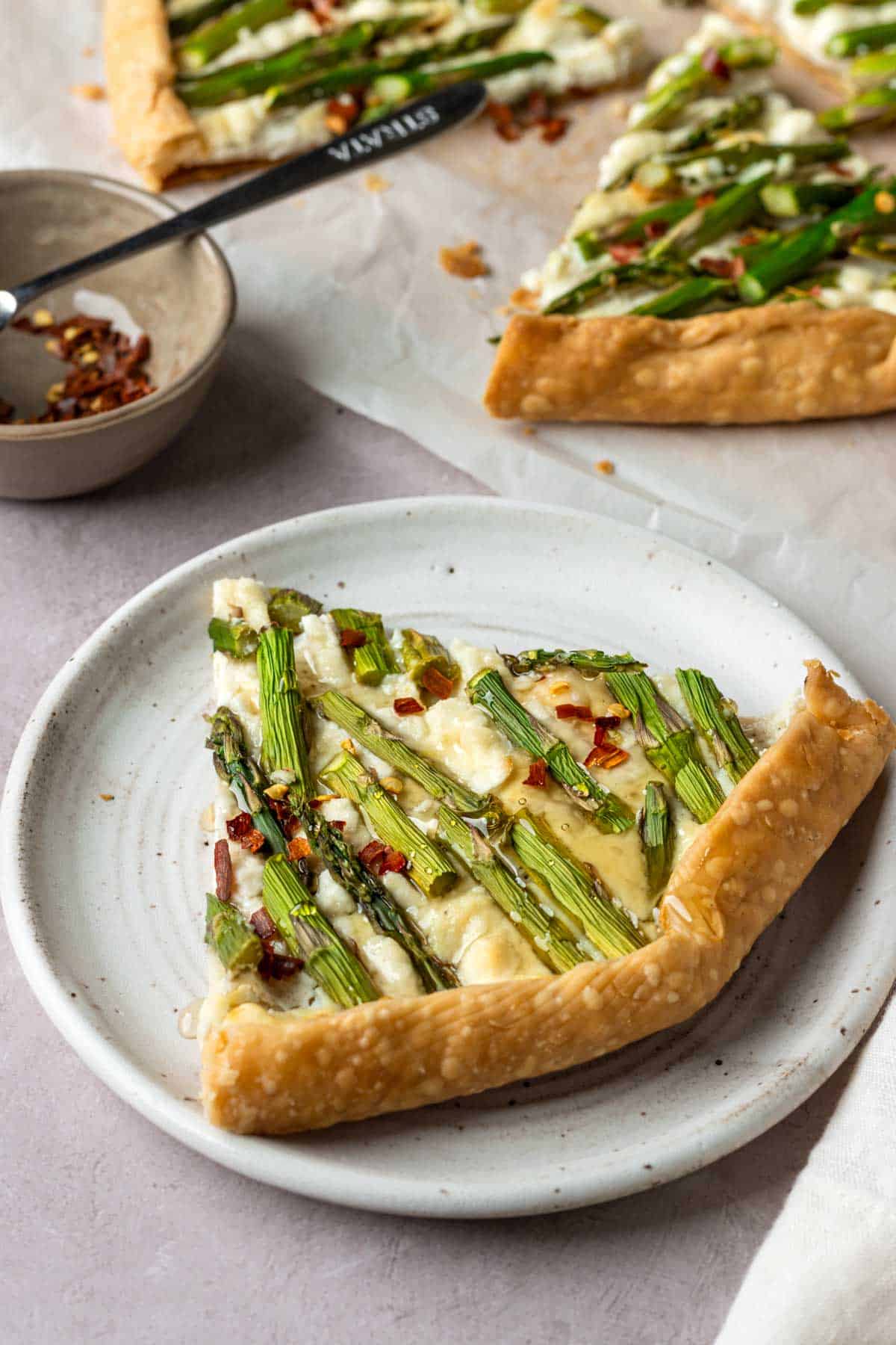 A slice of asparagus and cheese galette on a white plate.