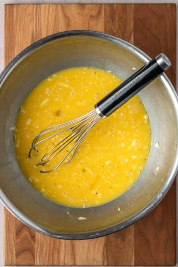 Whisked eggs and cheese in a large mixing bowl.